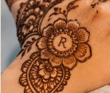 A letter worked into the centre of a mehendi flower
