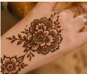 A large mehendi flower with personal detailing across the forearm