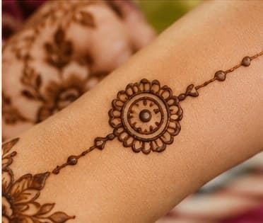 A small rakhi-shaped mehendi motif on a fine chain of dots
