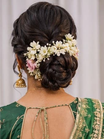 A low bun wrapped in white flowers